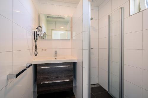 y baño con lavabo y ducha. en Hoogelandt 90A, en De Koog