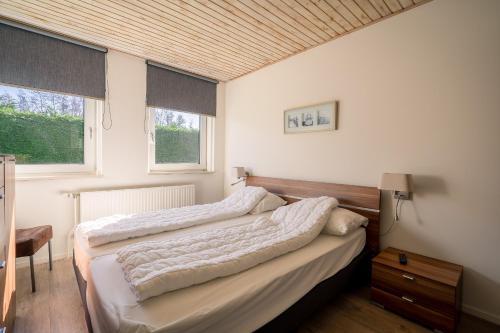 1 dormitorio con 2 camas y 2 ventanas en Hoogelandt 90A, en De Koog