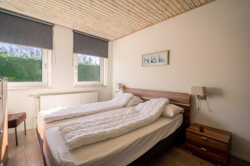a bedroom with two beds and two windows at Hoogelandt 90A in De Koog