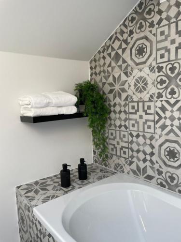 baño con bañera blanca y pared de azulejos en Le Trou du Bois, en Thimister