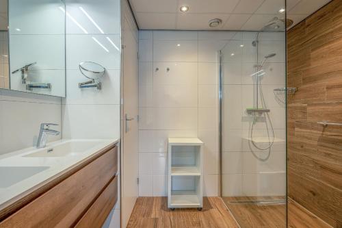 ein Bad mit einer Dusche und einem Waschbecken in der Unterkunft Appartementencomplex Juliana 72 in De Koog