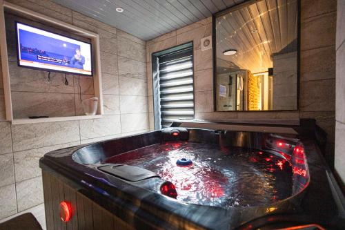 a large bath tub in a bathroom with a tv at Islington Romantic Studio - Jacuzzi & Garden in London