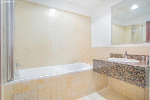 ein Badezimmer mit einer Badewanne, einem Waschbecken und einem Spiegel in der Unterkunft JBR The walk Rimal 6 - 3 Bedroom plus maid 2m walking to beach in Dubai