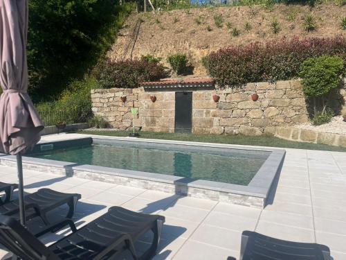 a swimming pool with two chairs and an umbrella at CRASTO PAYVA DOURO NATURE in Castelo de Paiva