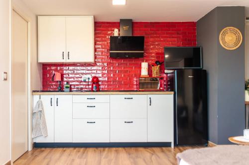 a kitchen with white cabinets and a red brick wall at Precioso ático en Valencia. in Valencia