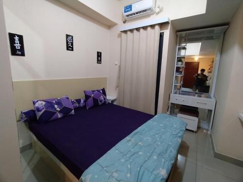 a bedroom with a bed with purple pillows and a mirror at JackProperty in Tambun-lobangbuaja