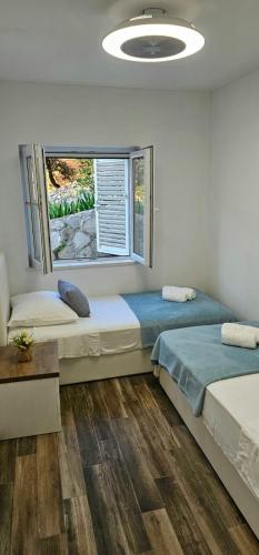 two beds in a room with a window at Holiday house Stela in Gdinj