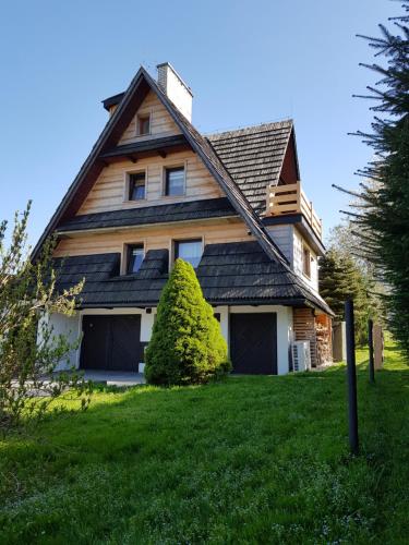 a house with a gambrel roof on a green lawn at Dom Górski Klimat-Willa 160 m2 z wewnętrzną sauną fińską, zniżki do Term Gorący Potok in Czerwienne