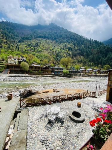 a view of a river with tables and chairs at Living Good - A Himalayan Boutique Stay in Gushaini