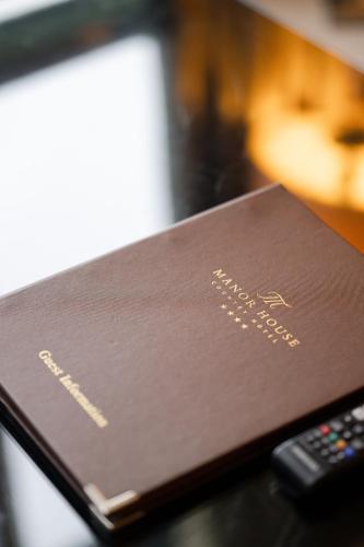 a brown passport sitting next to a remote control at Manor House Country Hotel in Enniskillen