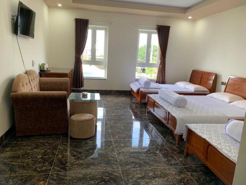 Zimmer mit 3 Betten, einem Sofa und einem Tisch in der Unterkunft HOÀNG GIA BẠC LIÊU in Bạc Liêu