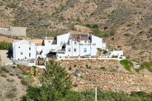 a large white house on top of a stone wall at Rambla Retreats Apartment Azul with shared pool & hot tub in Oria in Oria