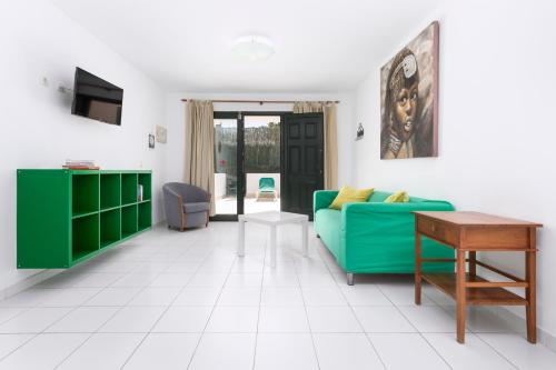 sala de estar con sofá verde y mesa en Apartamentos Erika - Adults Only, en Corralejo