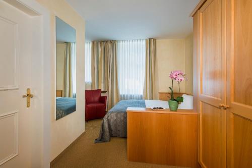 a bedroom with a bed and a table with a vase of flowers at Cresta Palace Celerina in Celerina