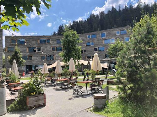 a building with tables and chairs and umbrellas at Modern LAAX apt, Swimming Pools, Wellness & Tennis in Laax