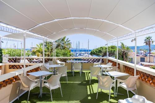 a restaurant with tables and chairs on a balcony at Le Rabelais in Le Lavandou