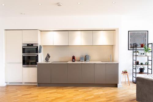 倫敦的住宿－Modern Chiswick Apartment，厨房铺有木地板,配有白色橱柜。