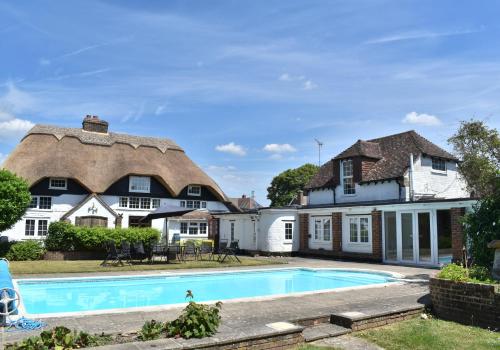 an estate with a thatched roof and a swimming pool at Beautiful Thatched Cottage with heated outdoor pool, Great for families & Dog Friendly! in Bosham