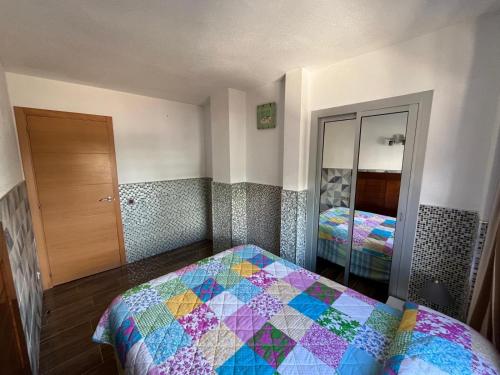 a bedroom with a quilt on a bed and a mirror at Apartamento Geminis I in Playa de Gandia