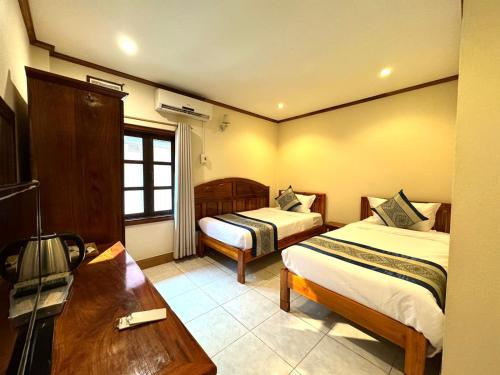 Habitación de hotel con 2 camas y escritorio en Heuang Paseuth Hotel 香帕赛酒店, en Luang Prabang