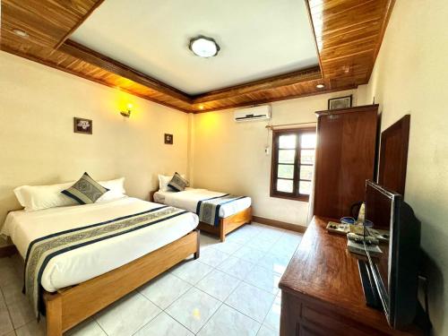 1 dormitorio con 2 camas y TV. en Heuang Paseuth Hotel 香帕赛酒店 en Luang Prabang