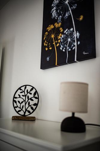 a table with a lamp and a painting on the wall at Apartman Spaß in Šabac