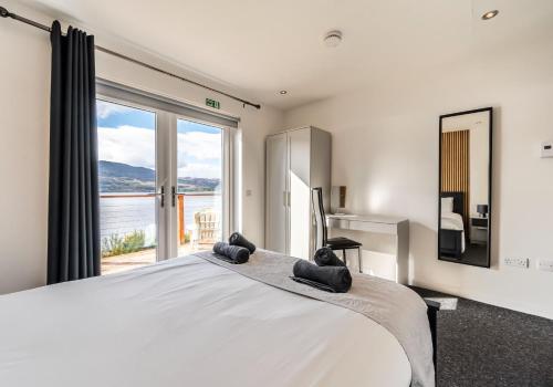 a bedroom with a large white bed with a large window at Shoreland Lodges - Cherry Lodge in Fort Augustus