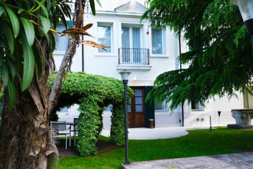 ein weißes Haus mit einem Tisch und einem Baum in der Unterkunft Villa Ca' Damiani Rooms & Apartments in Caneva