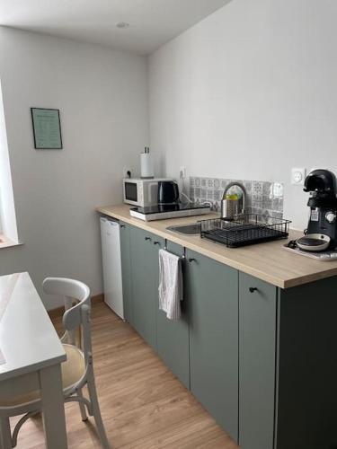 - une cuisine avec un évier et un comptoir avec une table dans l'établissement LA ROCHE, à Verdun-sur-Meuse