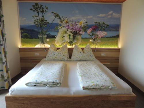 a bed with two pillows and a window with flowers at Ferienwohnungen Schöbringer in Weyregg