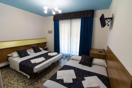una camera d'albergo con due letti e una finestra di BlueColors Hotel ex Hotel Lucy a Campalto