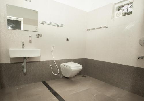 a bathroom with a toilet and a sink at Vythiri Silver Mist Villa by VOYE HOMES in Vythiri