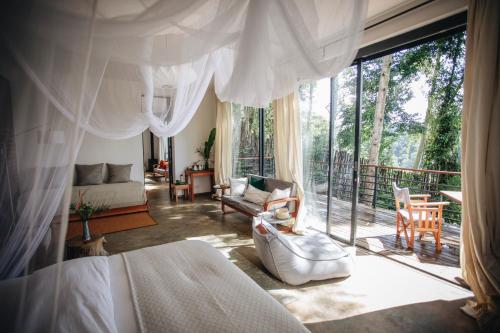 a bedroom with a bed and a living room with a balcony at Kaliwa Lodge in Moshi