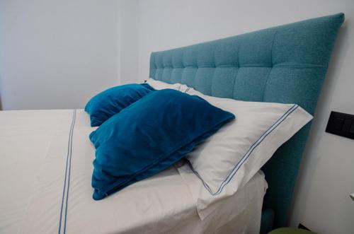 a bed with two blue pillows on it at 49 Downtown Pompeii in Pompei