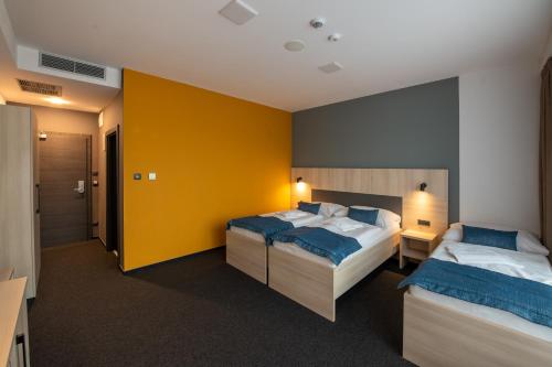 a bedroom with two beds and a yellow wall at Hotel Glamour in Kaluža