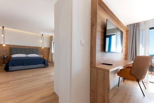 a bedroom with a bed and a desk with a television at Villa Senzen in Baška Voda