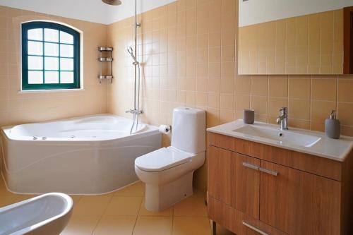 a bathroom with a tub and a toilet and a sink at Casa Santos in Albufeira