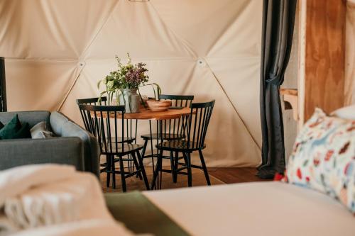 a small table with chairs and flowers in a tent at Dome Meadow 5 With Log Burning Tub At Tapnell Farm in Yarmouth