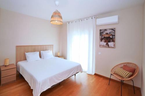 a bedroom with a white bed and a chair at Casa Santos in Albufeira