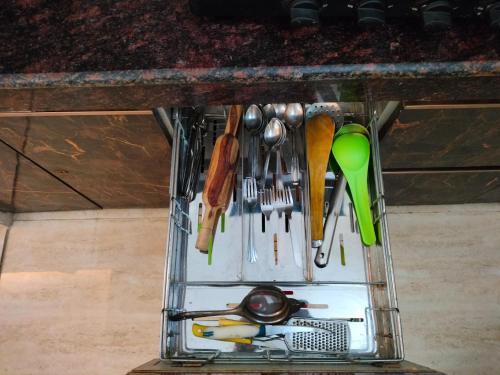 a container filled with utensils sitting under a counter at Blue Heart Home 1 BHK - Spacious Flat in Tapovan in Rishīkesh