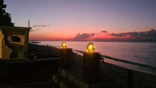 two candles in front of the ocean at sunset at Beach House Penida in Nusa Penida