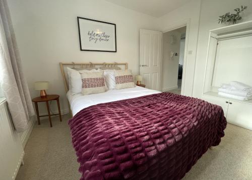 a bedroom with a large bed with a purple blanket at Apartment 4 St Georges in Cheltenham