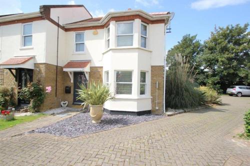 a white house with a potted plant in the driveway at The Zen Den in Southend-on-Sea