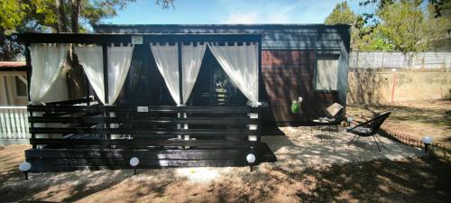 a black shed with curtains and a chair in a yard at Mobile home Ivan Vodice in Vodice