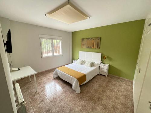 een groene slaapkamer met een bed en een raam bij Casa Maica in Lliria