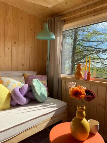 een slaapkamer met een bed en een vaas met bloemen op een tafel bij Tiny house Smûk in Tietjerk