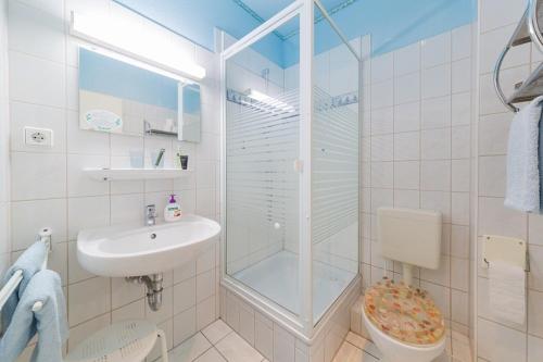 a white bathroom with a shower and a sink at Haus Troja in Warnemünde