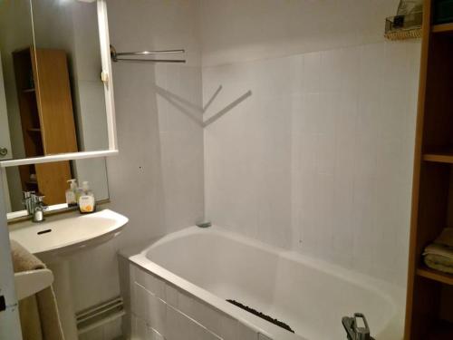 une salle de bain blanche avec une baignoire et un lavabo dans l'établissement Bel appartement double terrasse, au Barcarès