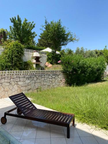 a bench sitting on a sidewalk next to a stone wall at Pine inn Xenia in Paliouri