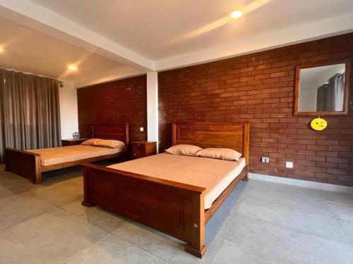 a bedroom with two beds and a brick wall at Hudakala Villa Hanthana in Kandy